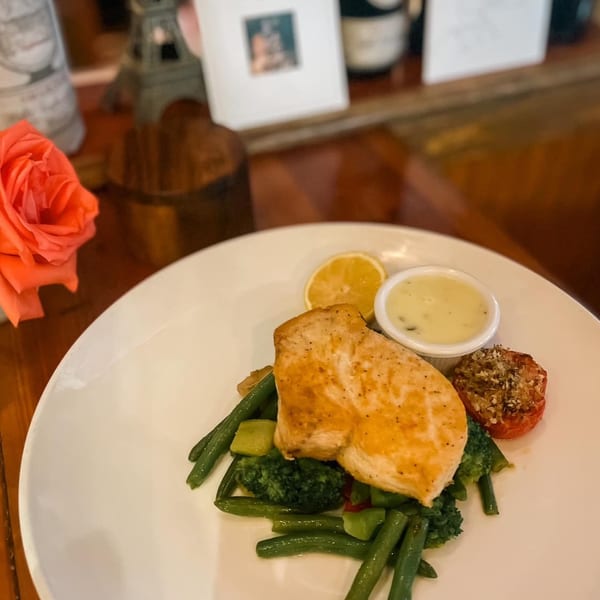 Grilled chicken breast with green beans, broccoli, roasted tomato, lemon, and a side of sauce.